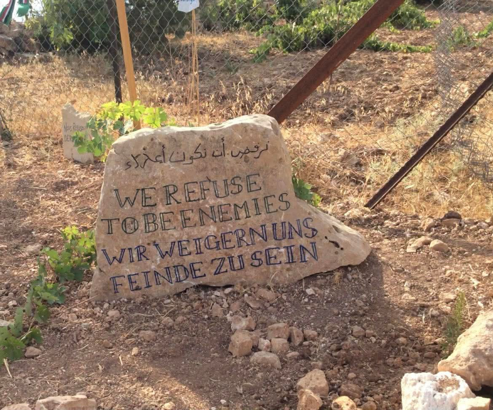 Grosse pierre à l'entrée de la Tente des Nations, en Palestine, sur laquelle est écrit : «Nous refusons d'être des ennemis.» | Photo : Anne Fortin